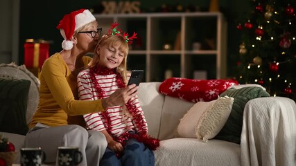 Grandmother and granddaughter making funny faces for christmas video call - Powered by Adobe
