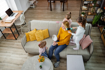 Three little girls are doing their mom's hair