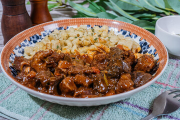 Delicious hungarian goulash with spaetzle, a traditional stew, resting on rustic table
