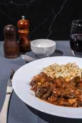 Delicious hungarian goulash with spaetzle, a traditional stew, served on a white plate