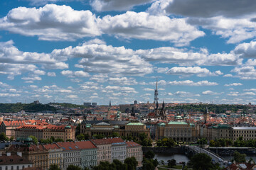 Panoramic cityscape under a vibrant sky filled with fluffy clouds, showcasing architectural...