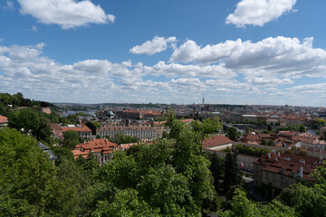 Panoramic cityscape view with red rooftops and a blue sky filled with puffy white clouds over the...