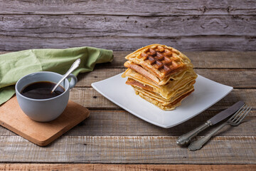 Breakfast consisting of a stack of waffles and a cup of coffee.