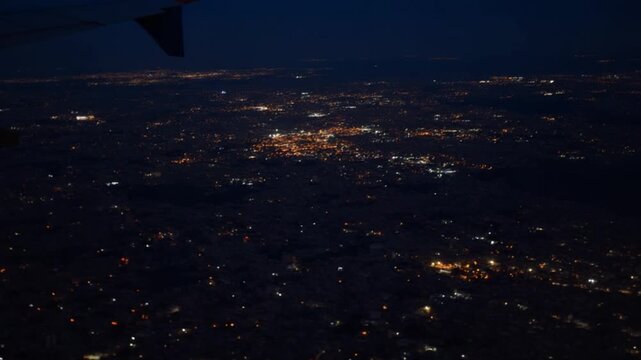 An aerial view of city lights sparkling in the night sky offers a stunning perspective on urban landscapes from above during a flight.