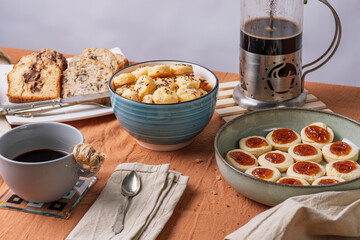 Afternoon snack or breakfast with coffee, banana bread, quince jam cookies, and cheese cookies with seeds.