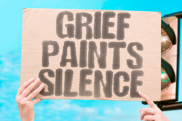 “Grief Paints Silence” displayed on a protest banner, symbolizing sorrow, expression, and muted...