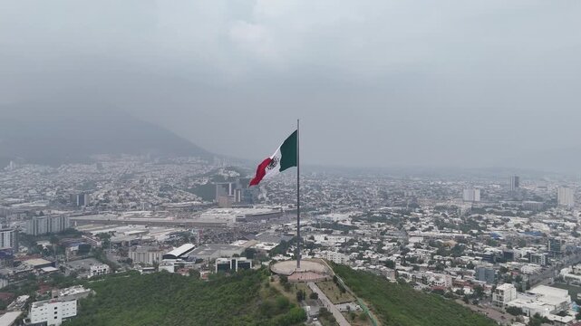 Toma a&eacute;rea de la bandera de M&eacute;xico ondeando en el Cerro del Obispado en Monterrey, Nuevo Le&oacute;n, durante un d&iacute;a nublado de septiembre en fiestas patrias.