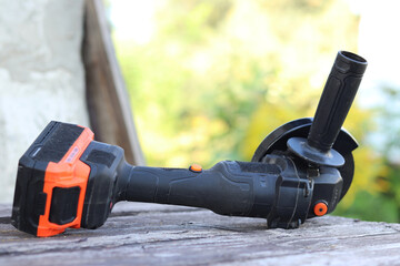 Cordless grinder lies on a wooden surface, close-up. Repair at the cottage or construction. Working...