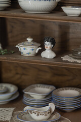 A small ceramic bust and dishes on a shelf in retro style.
