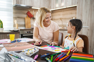 Mother and daughter enjoying arts and crafts at home in a bright kitchen during the afternoon