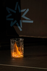 Flames erupting from a glass container standing on the floor.

