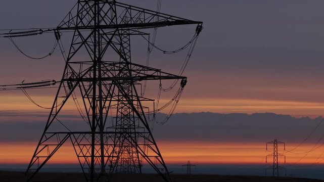 Majestic Power Grid Pylons Stretching Across a Rural English Landscape at Golden Sunrise