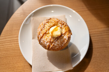 Delicious muffin with caramel and creamy topping on white plate in a cafe. High quality photo