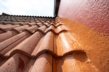 Roof tiles waterproofing membrane being applied on roof by construction worker