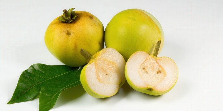 Fresh jambu fruits, cut and whole, with green leaves on white backdrop, showing details.