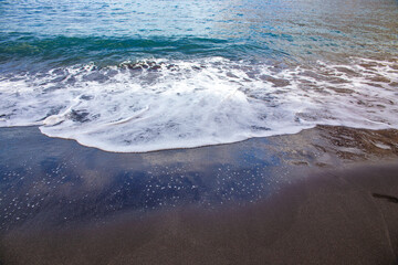 Ocean foam on black sand beach, Tenerife Canary Islands
