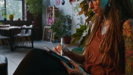 Side view closeup shot of young woman sketching using digital tablet while sitting on floor with cinematic lighting, copy space - Powered by Adobe