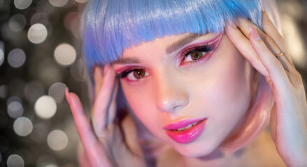 Beautiful young woman's face with perfect skin, wig and colourful makeup in neon light. Color neon portrait of beauty model with perfect smile, makeup and long eyelashes. Selective focus. Close-up