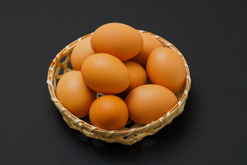 黒背景に映える竹かご入りの卵