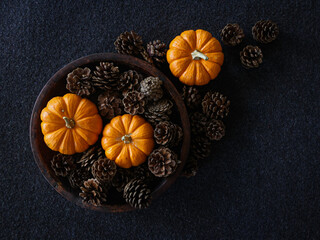 Overhead view of pumpkins and acorns flat lay on a dark textured surface for autumnal equinox day marking the beginning of Fall season. Fall background with copy space.