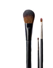 Close-up of two makeup brushes, one large, one small, black handles