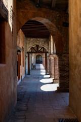 Sunlit Colonial Corridor with Arches and Wooden Chair