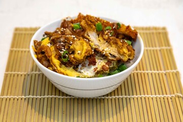 Katsudon Japanese-style cutlet pork (tonkatsu) with egg on rice, fresh chives, and sesame seeds