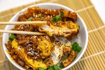 Katsudon Japanese-style cutlet pork (tonkatsu) with egg on rice, fresh chives, and sesame seeds