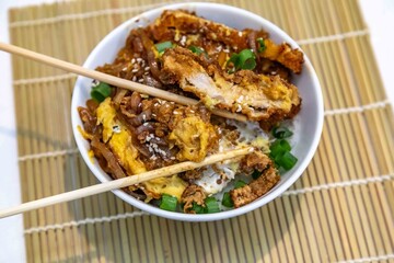 Katsudon Japanese-style cutlet pork (tonkatsu) with egg on rice, fresh chives, and sesame seeds
