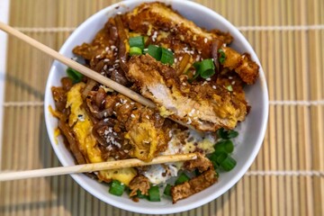 Katsudon Japanese-style cutlet pork (tonkatsu) with egg on rice, fresh chives, and sesame seeds