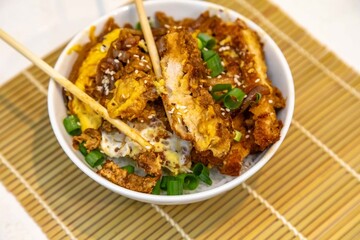 Katsudon Japanese-style cutlet pork (tonkatsu) with egg on rice, fresh chives, and sesame seeds