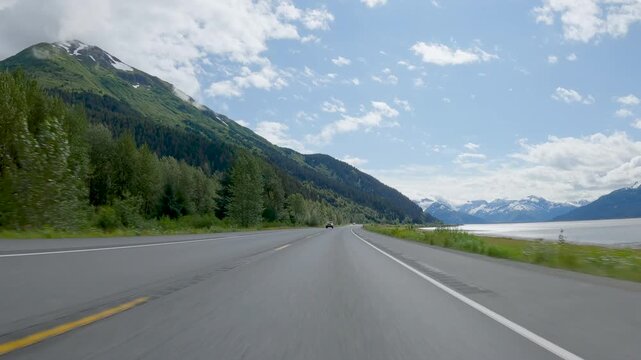 POV Driving a car on asphalt road in Alaska. Road toward Seward. Blue sky on sunny day