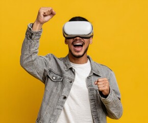 Fototapeta premium A man wearing virtual reality headset celebrates a victory against a vivid yellow backdrop.