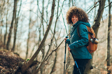 Naklejka premium Young hiker exploring forest trail with backpack and trekking poles