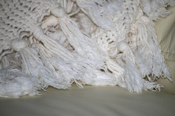 A cozy handmade blanket with chunky tassels on a sofa