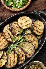 Grilled slices of eggplant with microgreens served on wooden table, flat lay