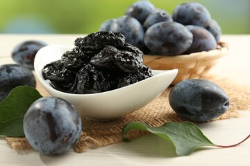 Dried prunes and fresh plums on wooden table, closeup
