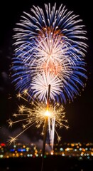 Colorful fireworks and sparkler illuminating the night sky above city lights, festive celebration atmosphere symbolizing joy, excitement, and holiday festivities