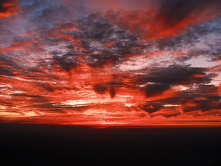 Fototapeta premium Dramatic Red Sunset Over Mountain Horizon with Vibrant Clouds