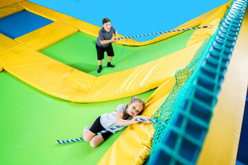 Kids playing in trampoline center jumping and climbing with rope