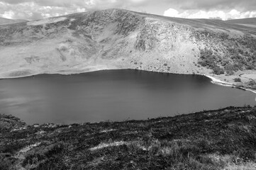 A black and white photo of a lake with a mountain in the background