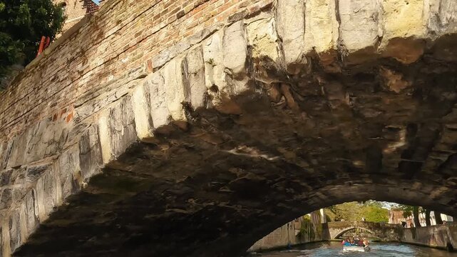 Quiet canal-side view in Bruges, Belgium, showing a historic stone bridge and medieval brick house