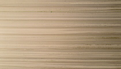 Top down aerial view of parallel vehicle tracks creating an abstract linear pattern on a sandy beach or dirt road