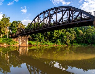 Fototapeta premium Rusty bridge over a calm river, lush greenery