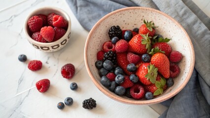 Colorful assortment of fresh berries in decorative bowls on a marble surface