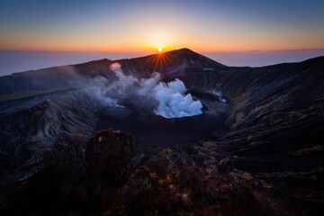 Active volcano erupting steam at sunrise with dramatic sky