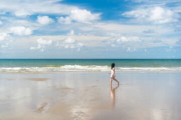 Fototapeta premium asian child summer at sea or kid girl happy walking alone on beach playing sand and daylight blue sky by travel or tourist children to young people vacation holiday relax at island rayong in thailand