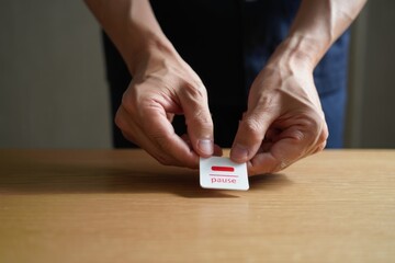 Hands holding a pause button, symbolizing a moment of rest