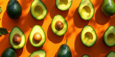 Overhead view of fresh avocado halves on bold orange background, natural light highlighting shapes and pattern