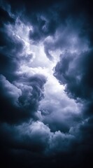 Fototapeta premium Dark, swirling storm clouds frame a bright, hazy center. Shades of blue and gray dominate, suggesting a powerful, ominous weather event